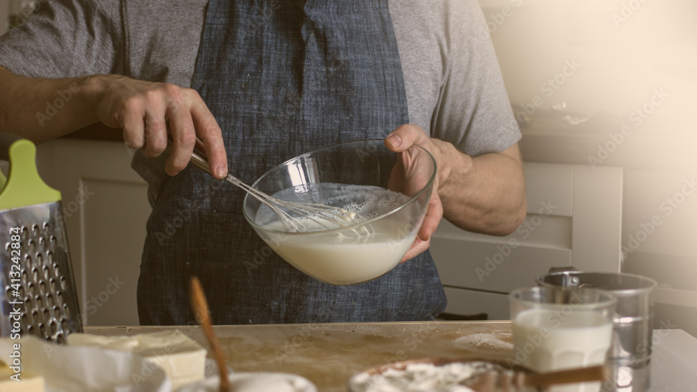 A male baker kneads bread dough in his kitchen. Home baker A male baker kneads bread dough in his kitchen. Home baker