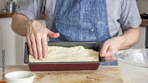 A man without a face in an apron holds raw bread dough in his hands, a home baker. Authentic home cooking hobby