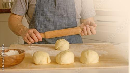A man rolls dough on the table in the kitchen. Homemade bread baking