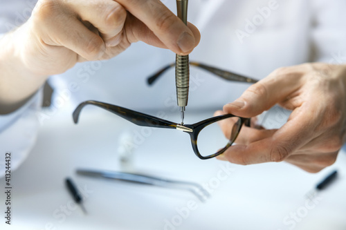 Fotografie eyewear repair service - optical technician repairing eyeglass frame with screwd