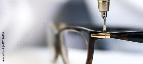 eyewear repair service - screwing the screw in eyeglass frame. copy space photo