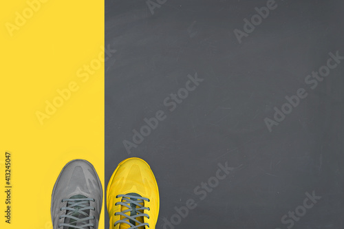 Yellow and grey pair of sneakers on gray-yellow background. Trending colors of 2021. Minimal concept.
