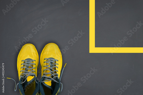 Yellow sneakers on grey background with geometric shape on it. Trending colors of 2021. Minimal concept.