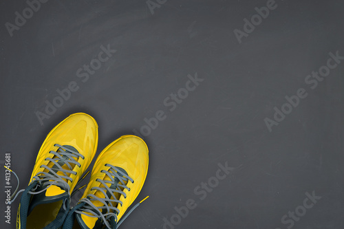 Yellow sneakers on grey background. Trending colors of 2021. Minimal concept.