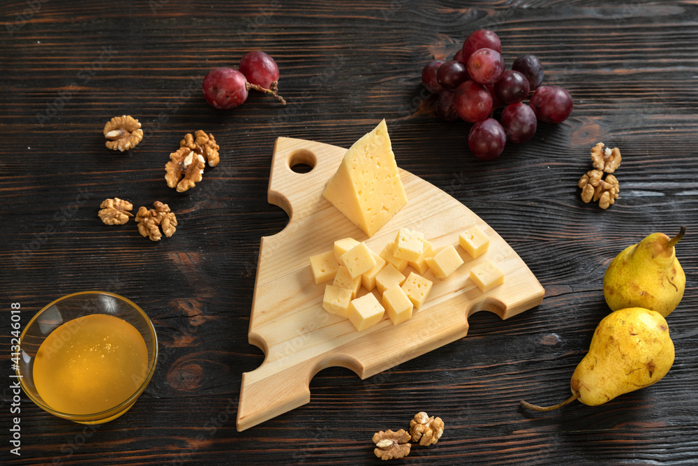 Cheese, pears and nuts on a wooden cutting board