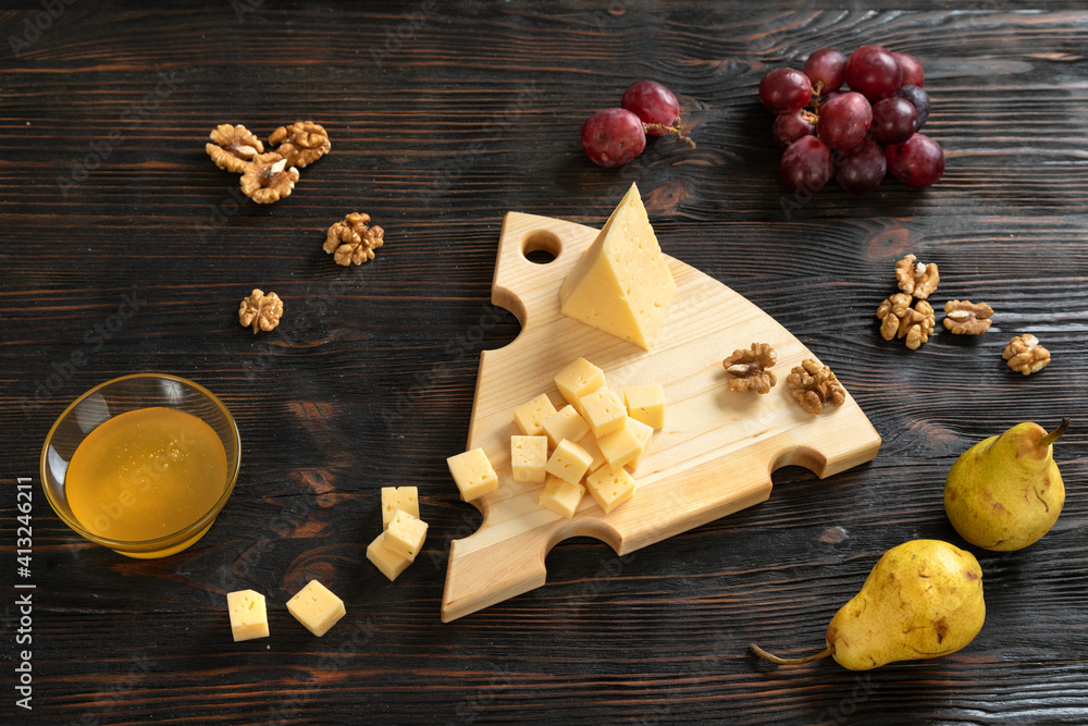 Cheese, pears and nuts on a wooden cutting board