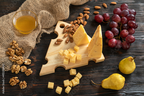 Obraz na płótnie Cheese, pears and nuts on a wooden cutting board w salonie