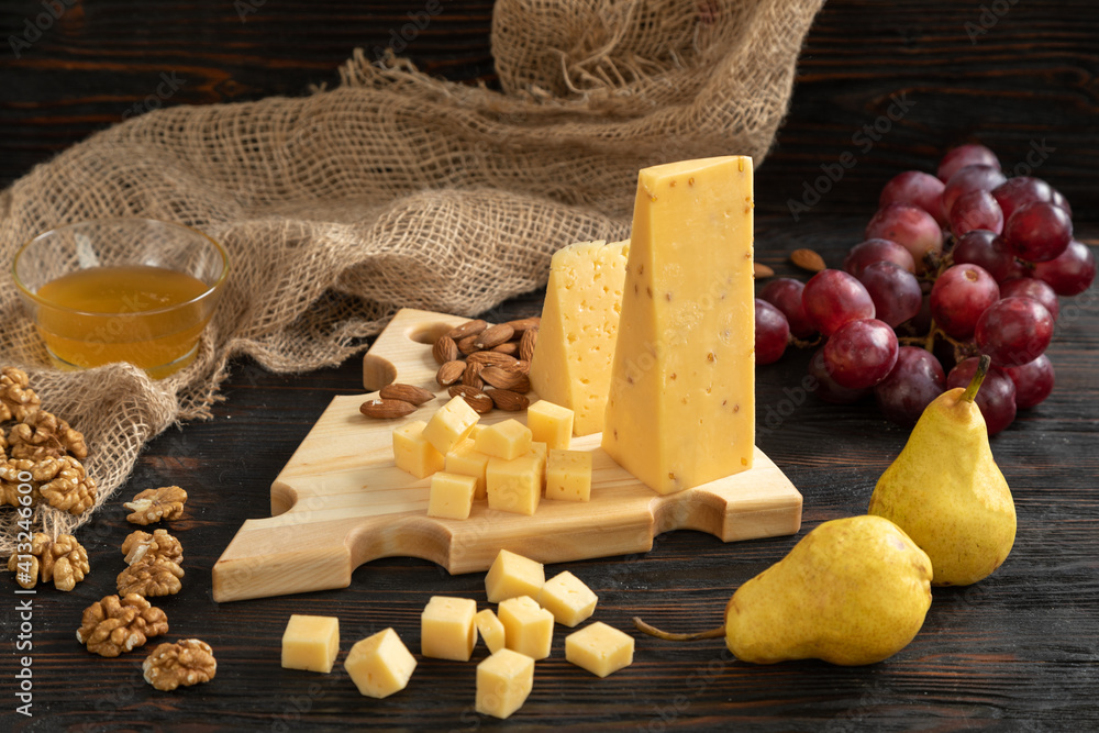 Cheese, pears and nuts on a wooden cutting board