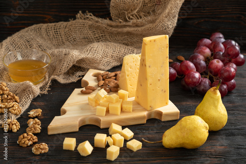 Obraz na płótnie Cheese, pears and nuts on a wooden cutting board w salonie