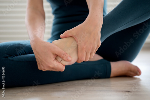 Tableau sur toile Woman in sportswear kneading feet before class