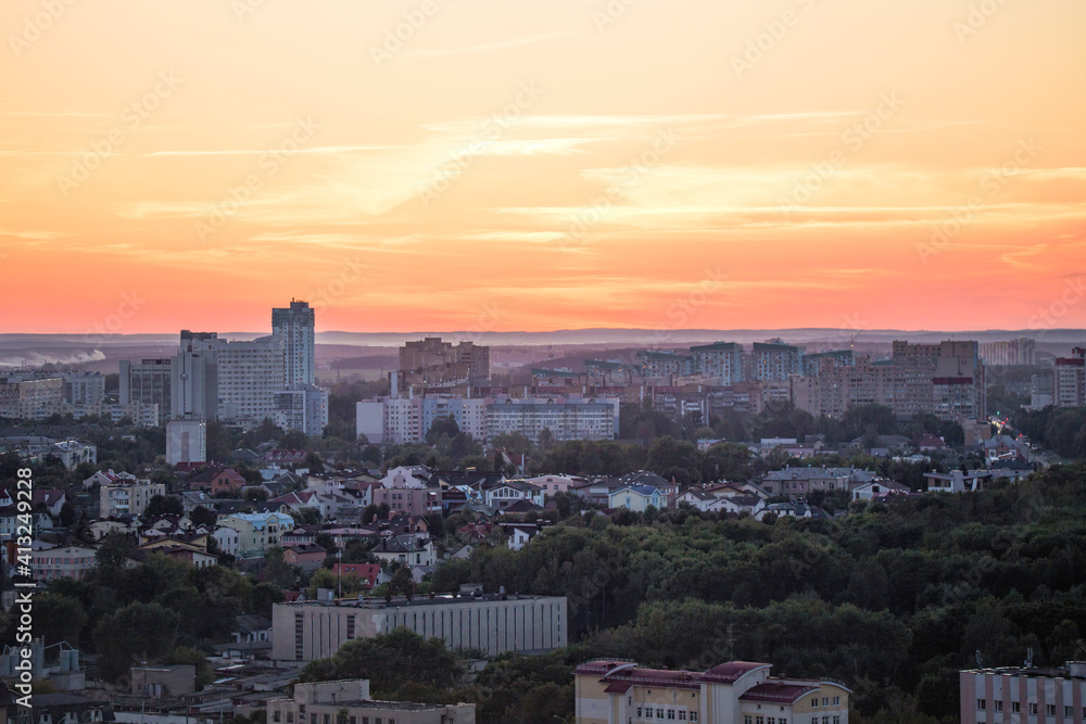 Panorama of a big city from a great height at sunset. View of the city of Minsk. Colorful red sky, many different houses and green trees on the streets of the city.
