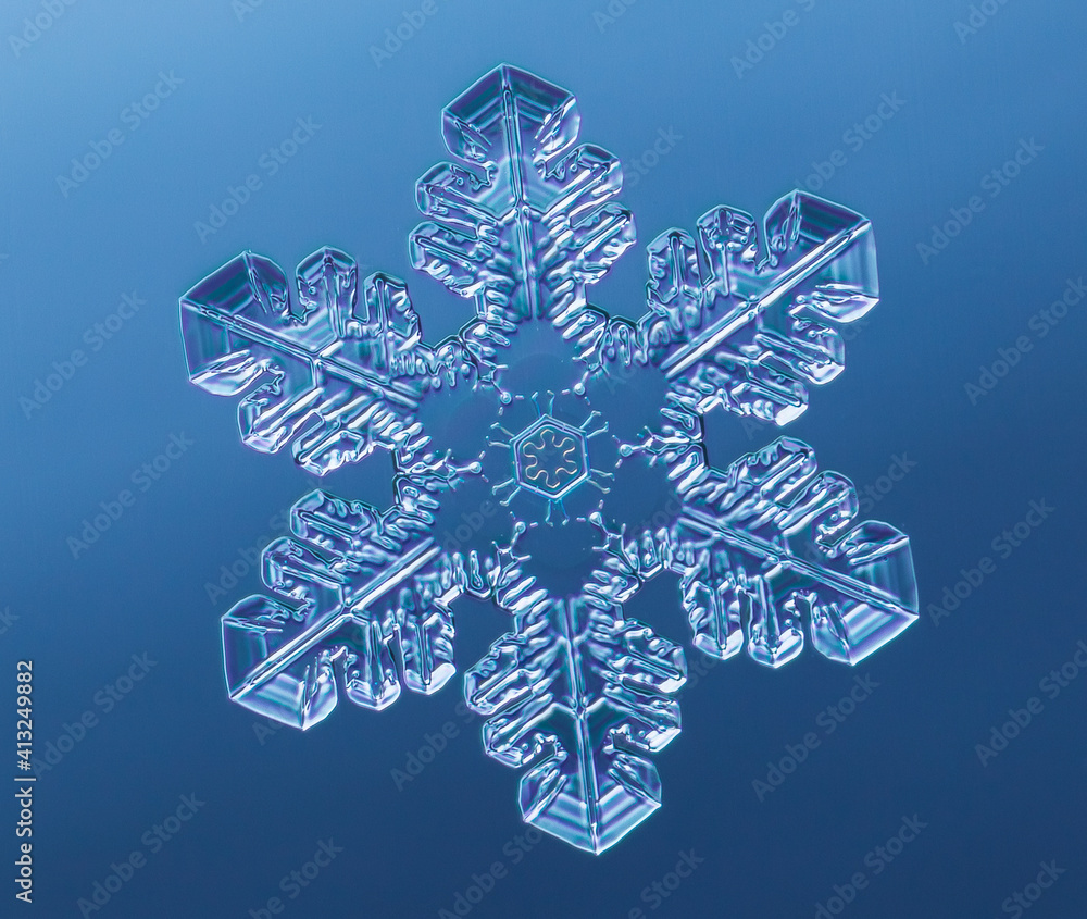 Snowflake on smooth gradient background. Macro photo of real snow crystal on glass surface. This is small snowflake with unusual pattern. Snowflake on smooth gradient background. Macro photo of real snow crystal on glass surface. This is small snowflake with unusual pattern.