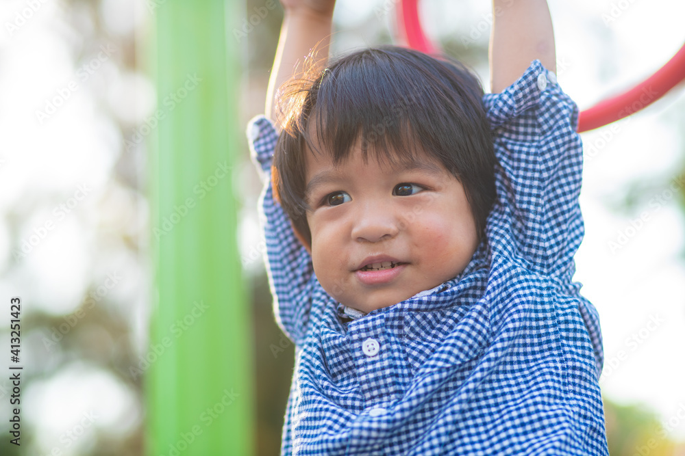 Happy asian child boy climb on playground bar in city park Happy asian child boy climb on playground bar in city park