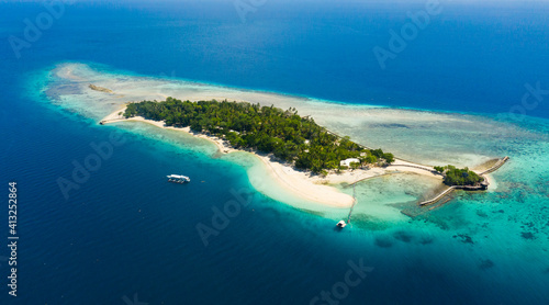 Little Liguid Island with a sandy beach and azure water surrounded by a coral reef and an atoll, aerial view. Little Cruz Island, Philippines, Samal.