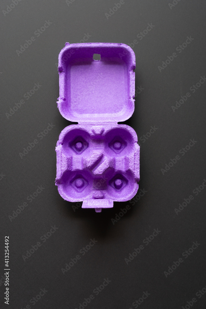 Violet, cardboard egg box on a black background. Violet, cardboard egg box on a black background.