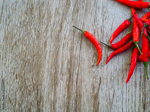 Red peppers stacked together on a wooden floor, taken from the top corner.