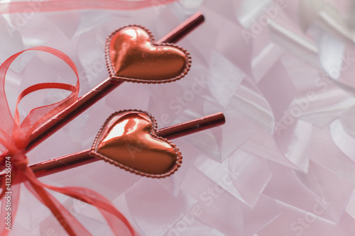 Red glossy hearts on the sticks tied with a ribbonon the pastel pink background with a copy space photo