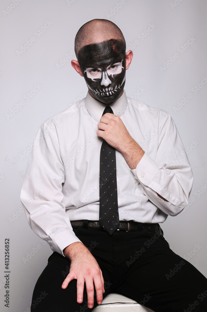 a man in halloween makeup as a dead man with a black skull, bald head and tie a man in halloween makeup as a dead man with a black skull, bald head and tie