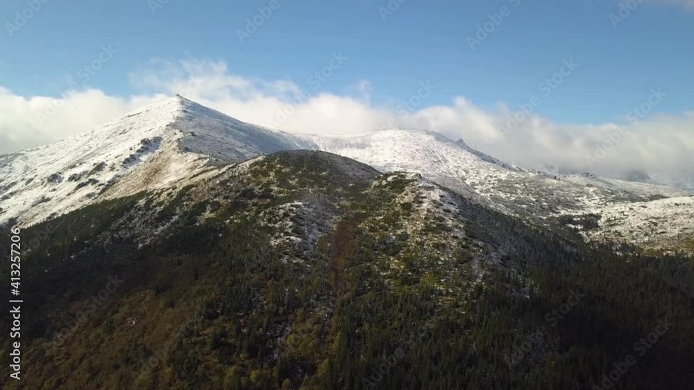 Aerial view of majestic mountains covered with green spruce forest and high snowy peaks. Aerial view of majestic mountains covered with green spruce forest and high snowy peaks.