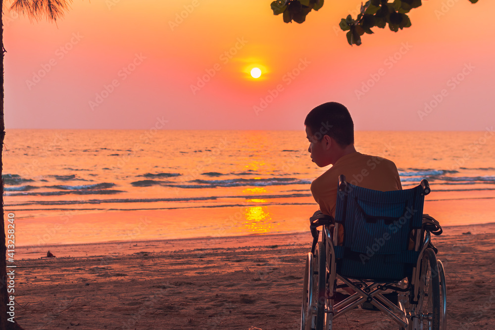 Asian special child on wheelchair on the sea beach with sunset on travel time in holiday family and learning about nature around the sea,Lifestyle in the education age kids,Happy disabled kid concept.