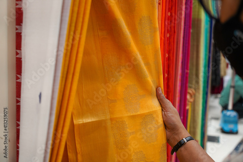 hand of a lady selecting yellow colored saree photo