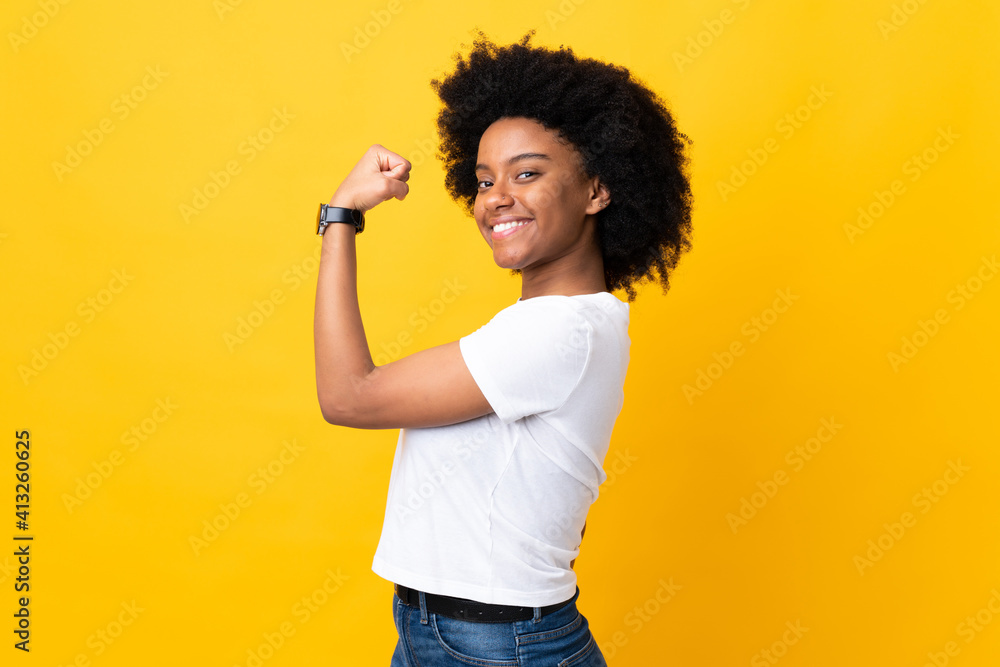 Young African American woman isolated on yellow background doing strong gesture Young African American woman isolated on yellow background doing strong gesture