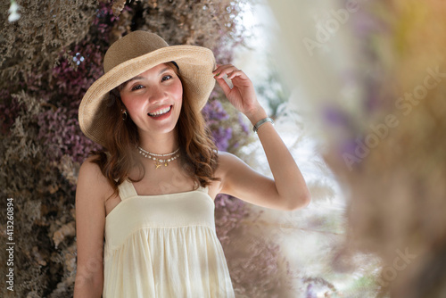  Sweet smiling Asian woman wearing a hat and taking pictures with dried flowers on the back. 