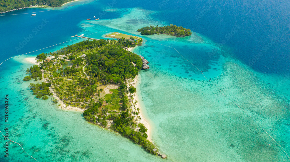 Aerial drone of Seascape with beautiful beach and tropical Malipano island with palm trees by coral reef from above. Philippines, Samal.