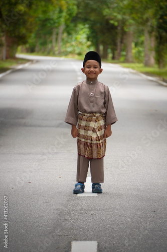 A Malay boy in Malay traditional cloth showing his happy reaction during Eid Fitri or Hari Raya celebration. © Yunus Malik