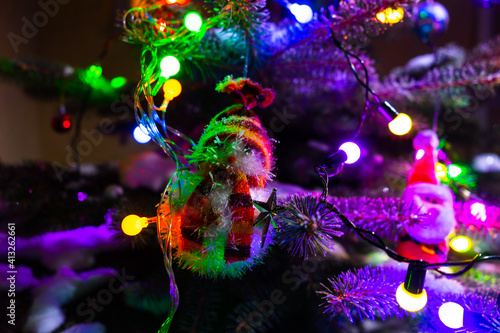 Christmas tree and snowman. winter nature christmas background, frozen spruce, glitter lights. View through the frost pine branch.