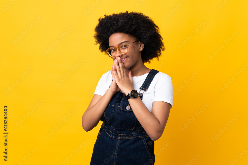 Young African American woman isolated on yellow background keeps palm together. Person asks for something Young African American woman isolated on yellow background keeps palm together. Person asks for something