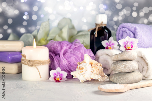 Massage stones  seashell  burning candles  rolled towels  soap  massage oil  sea salt  flowers  abstract lights. Spa resort therapy composition