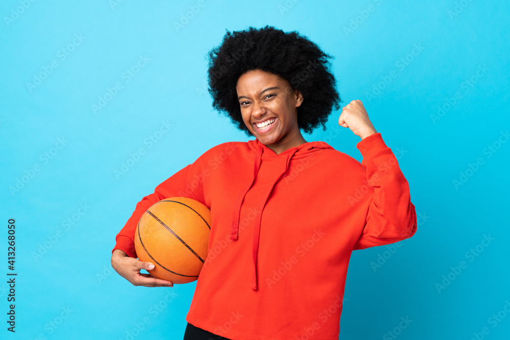 Young African American woman isolated on blue background playing basketball and proud of himself