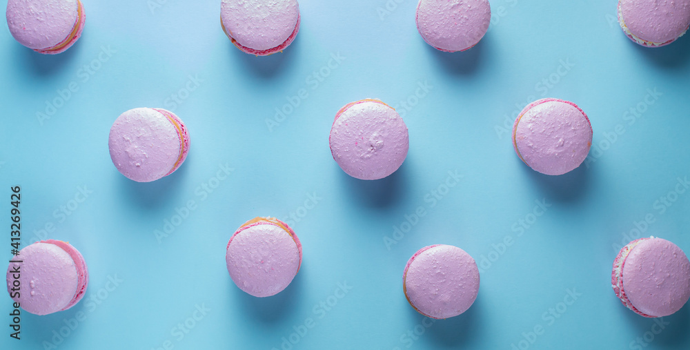 French macaroni cakes in pink on a white oval plate on a blue background. French macaroni cakes in pink on a white oval plate on a blue background.