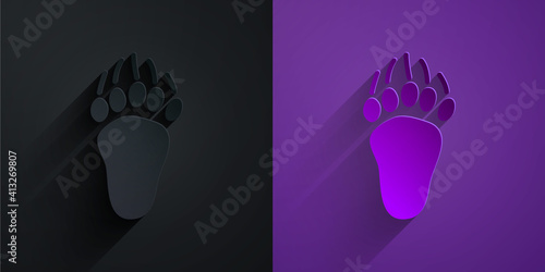 Paper cut Bear paw footprint icon isolated on black on purple background. Paper art style. Vector.