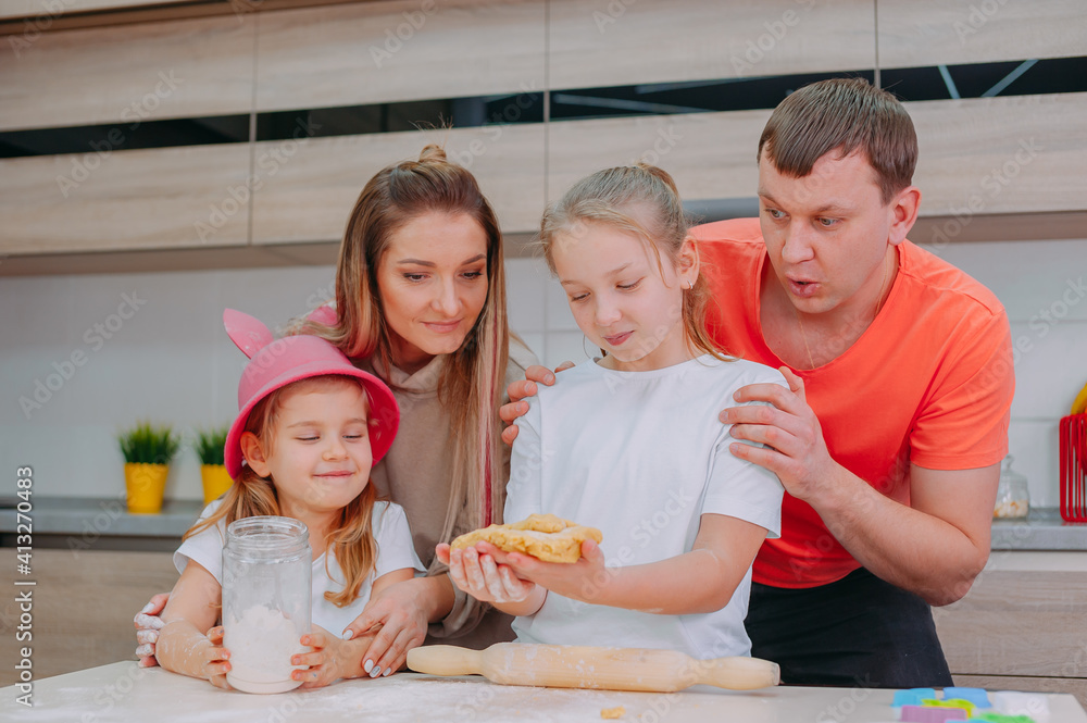 Mom with Father teaches two daughters to cook dough in the kitchen. Mom with Father teaches two daughters to cook dough in the kitchen.