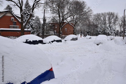 Montreal, Canada - February 2019: Heavy snowfall, with snow covering parked cars in a street