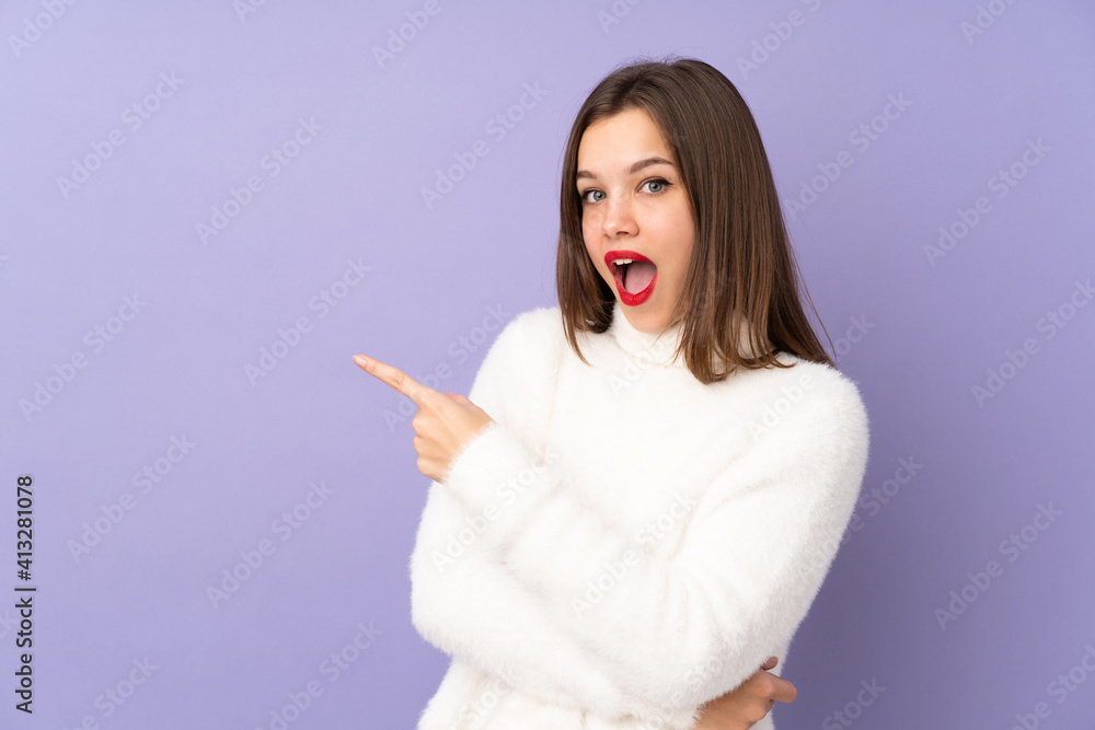 Teenager girl isolated on purple background surprised and pointing side Teenager girl isolated on purple background surprised and pointing side