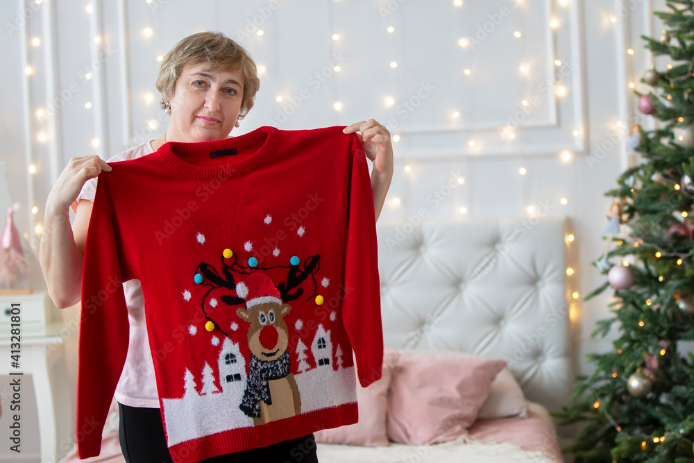An elderly woman tries on a red holiday sweater at Christmas.