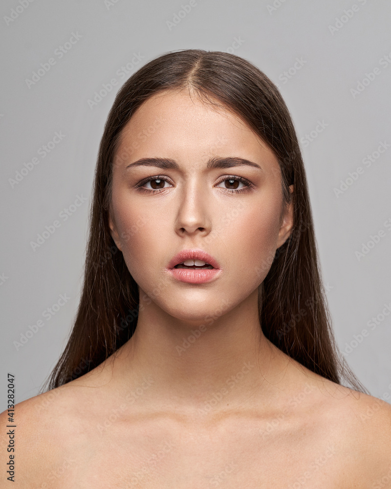 Young beautiful female model close-up studio beauty portrait. Girl with natural make-up and long brunette straight hair. Calm woman looking at you Young beautiful female model close-up studio beauty portrait. Girl with natural make-up and long brunette straight hair. Calm woman looking at you