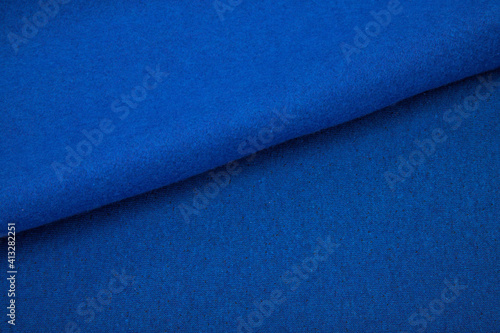Pleats on fabric, knitted material of bright blue color, folds