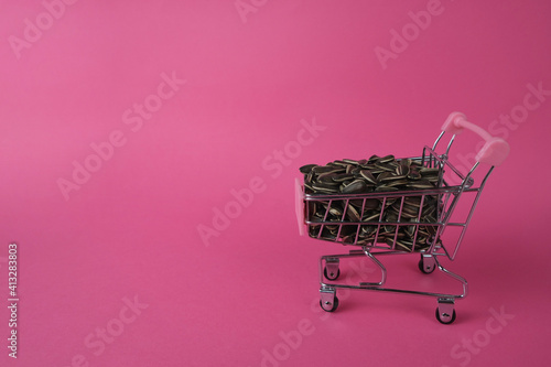 Seeds in a cart on a pink background. View from above. Sales concept. Banner with copy space. 