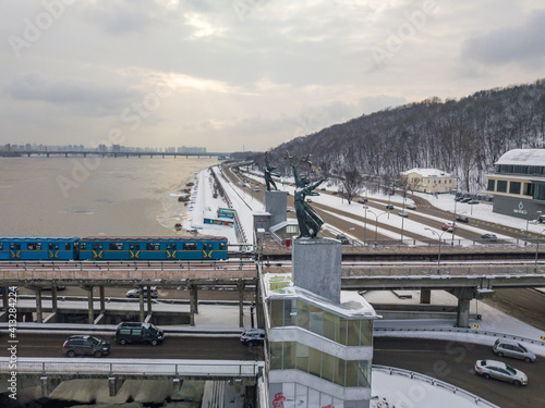One metro train on a snow-covered metro bridge in Kiev. Cloudy winter morning. Aerial drone view.