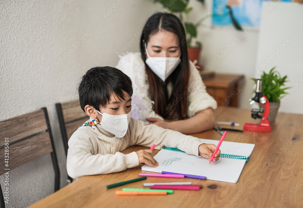 Asian mother drawing with little kid at home while wearing surgical face masks for coronavirus outbreak - Mother and child love Asian mother drawing with little kid at home while wearing surgical face masks for coronavirus outbreak - Mother and child love