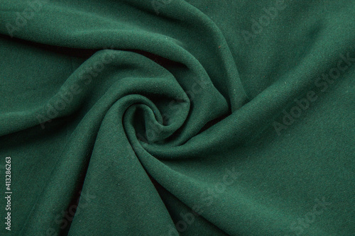 Pleats on fabric, knitted material of green color, folds