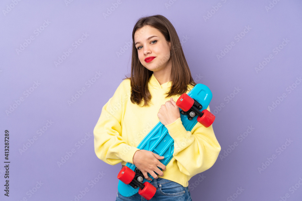 Teenager girl isolated on purple background with a skate with happy expression Teenager girl isolated on purple background with a skate with happy expression