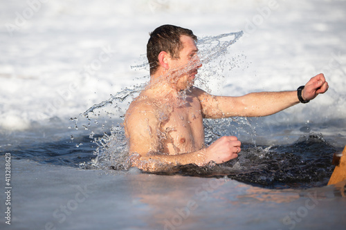 A man plunges into an ice-hole during the winter festival of the baptism of Jesus. A man swims in the ice-hole in winter. Walrus people. © Светлана Лазаренко