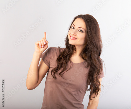 Beautiful business woman pointing the finger up . Casual closes on brunette model on blue background. Happy toothy smile. Closeup