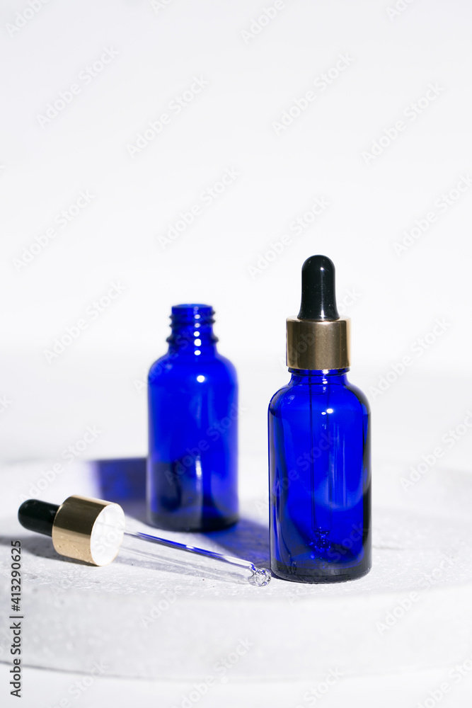 Blue glass dropper bottle on the white background with black and golden caps beauty industry skincare and treatment beautiful composition