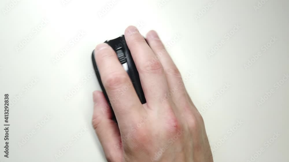 Close-up of male hand clicking mouse. Black computer mouse on a work desk. Working with a PC and clicking on the mouse.
